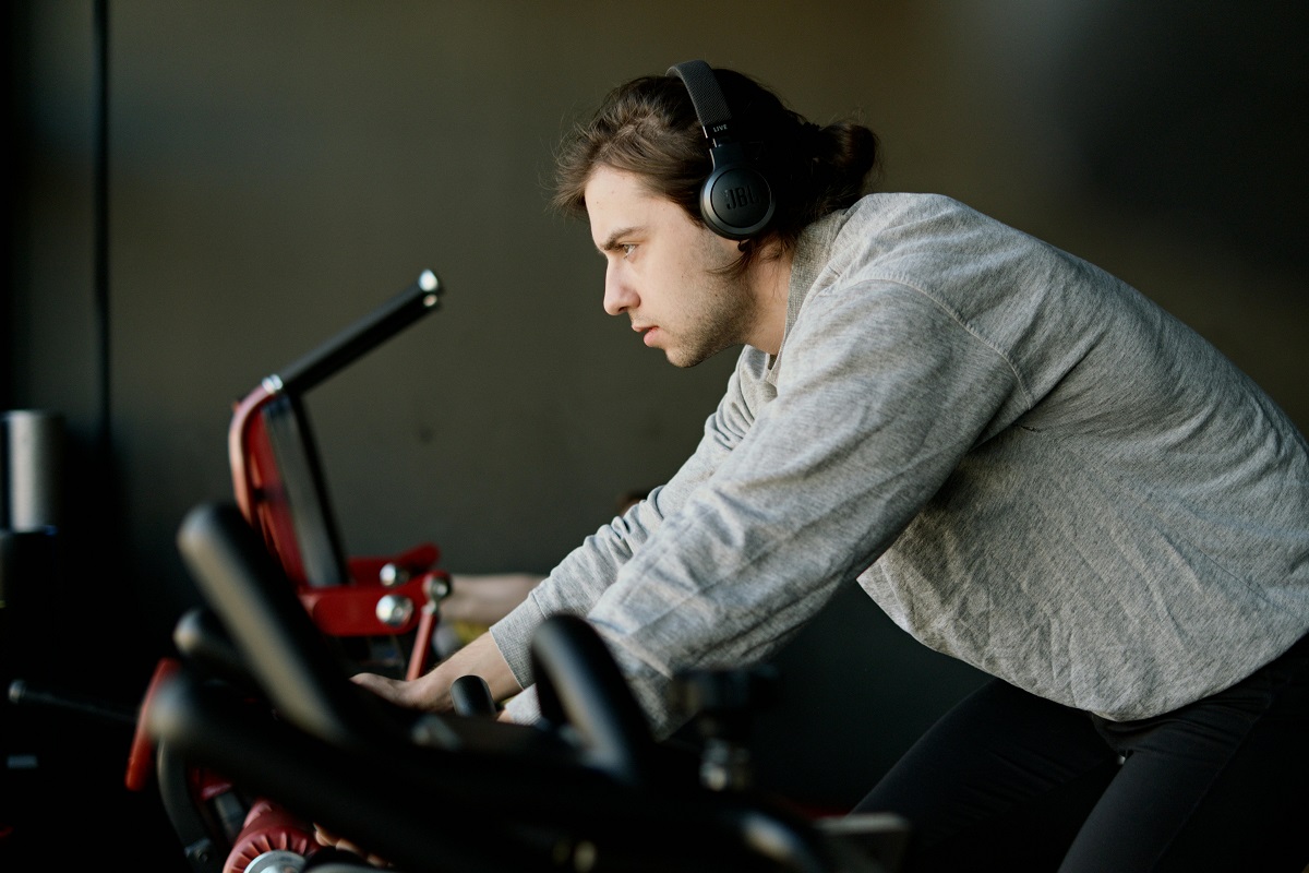man exercising on a stationary bicycle while listening to music through his headset