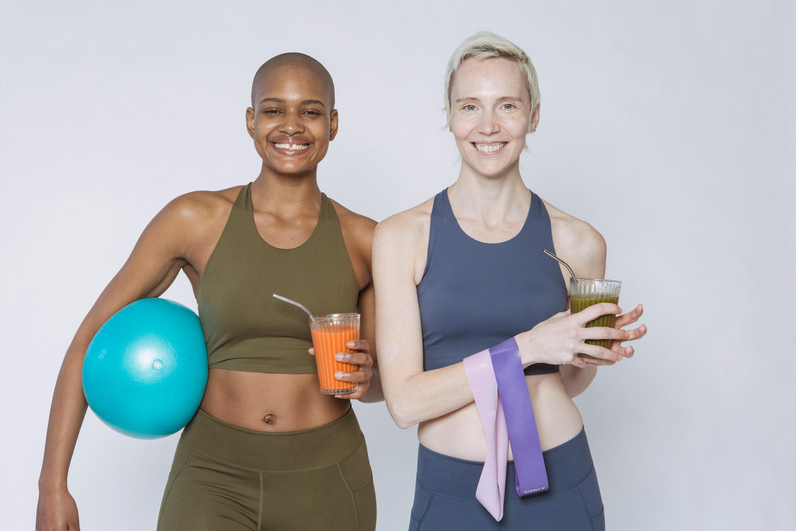 two women in activewear holding glasses of smoothie